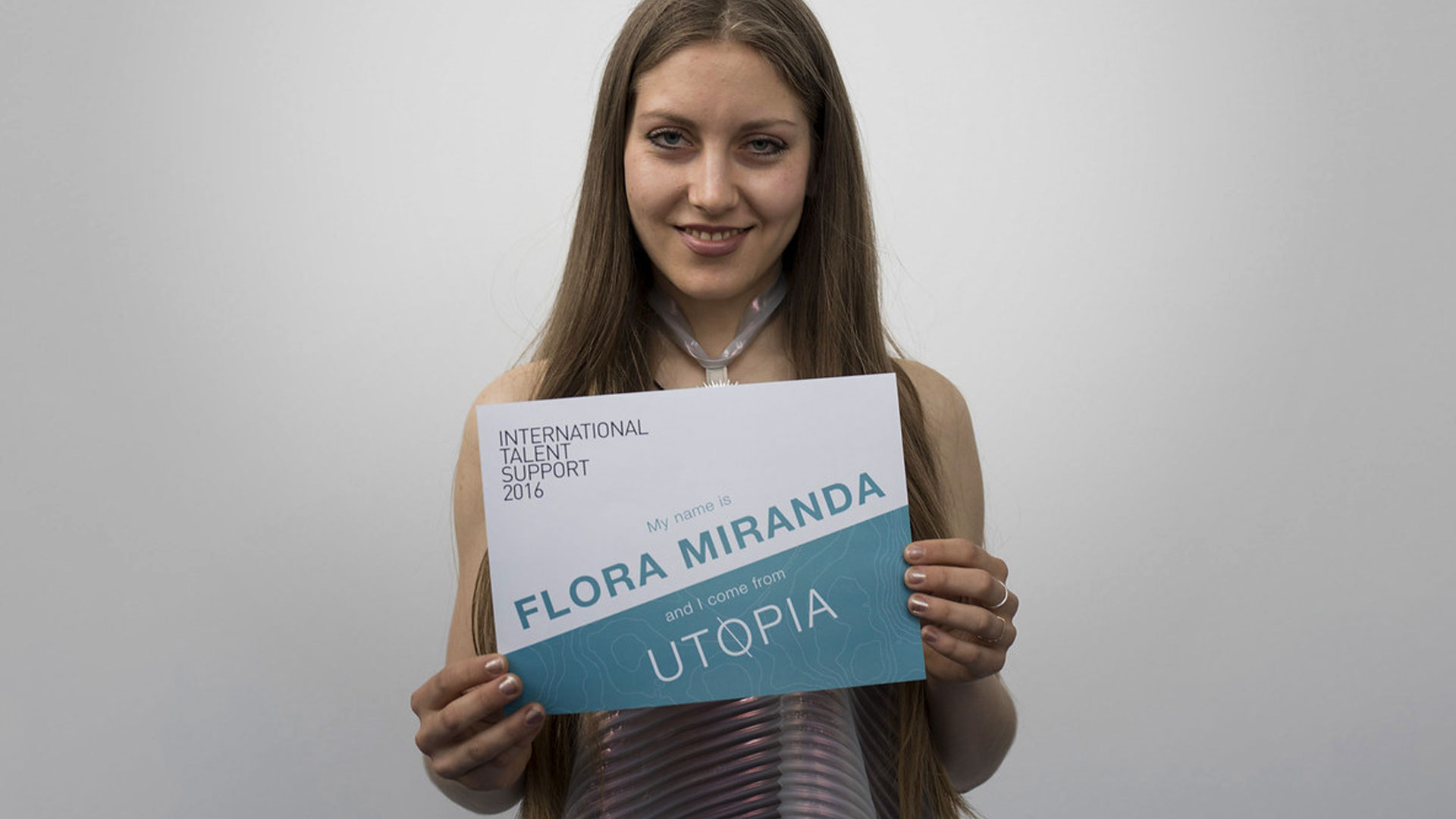 a woman holding up a sign that says flora miranda utopia