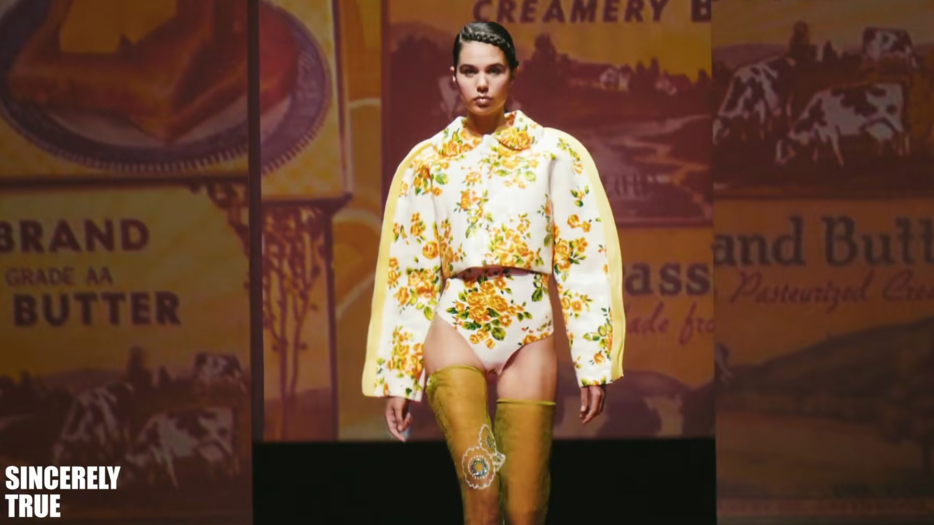 a model walks down the runway in a yellow outfit