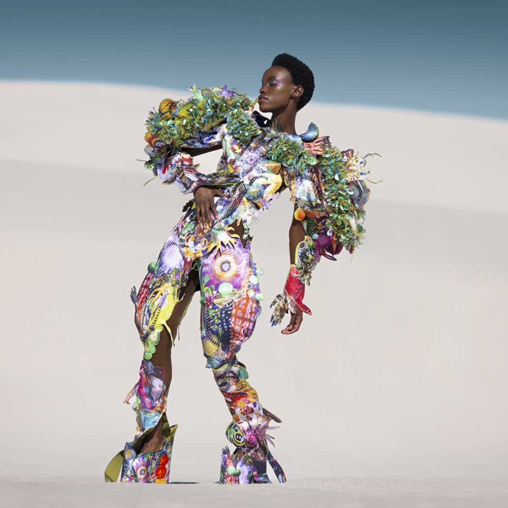 a woman in a colorful outfit standing in the sand