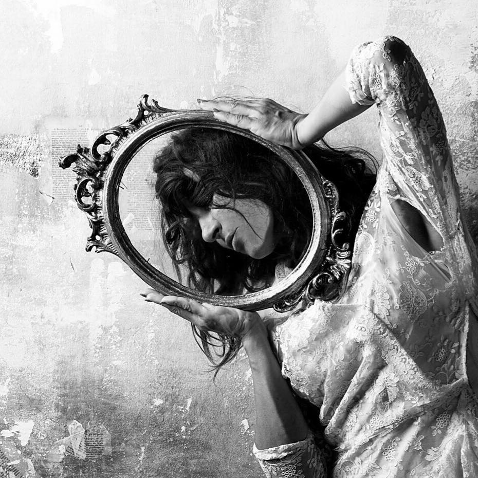 a woman holding a mirror in front of her face