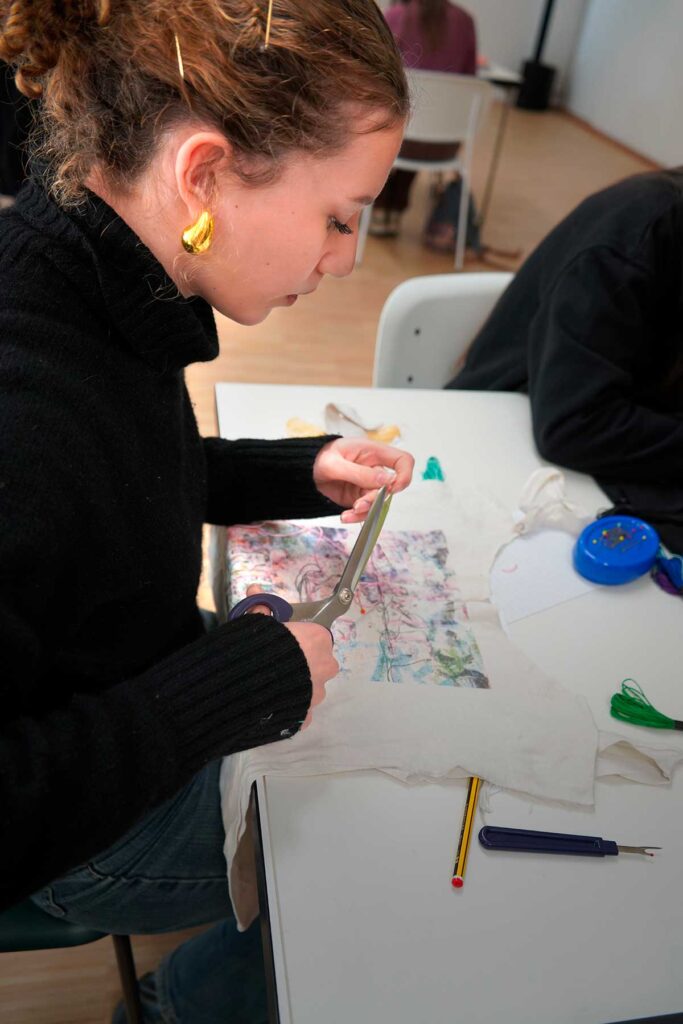 a woman sitting at a table with a pair of scissors