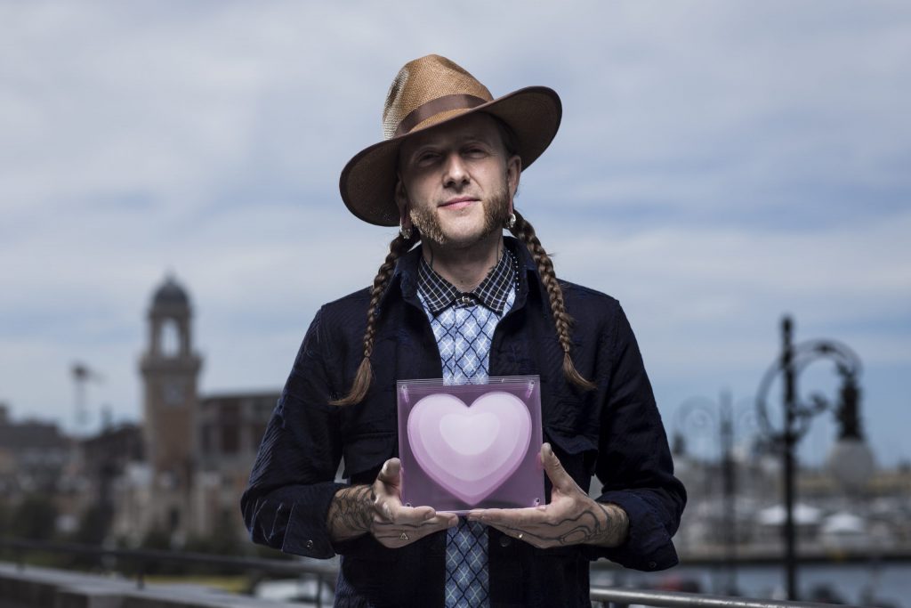 a man in a hat holding a heart shaped box